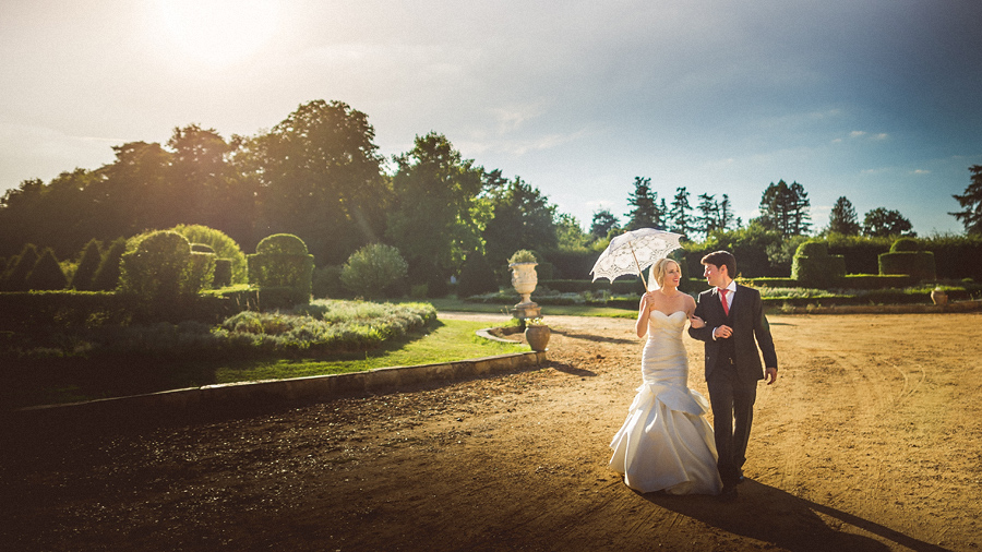 bride and groom walking happily with umbrella in france