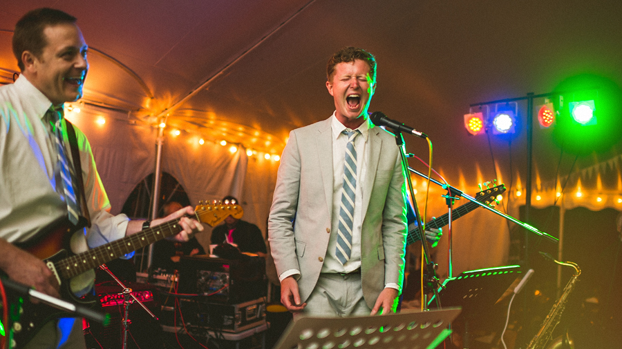 groom singing on stage with wedding band