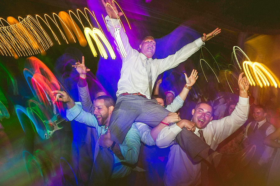 guys holding groom up while dancing