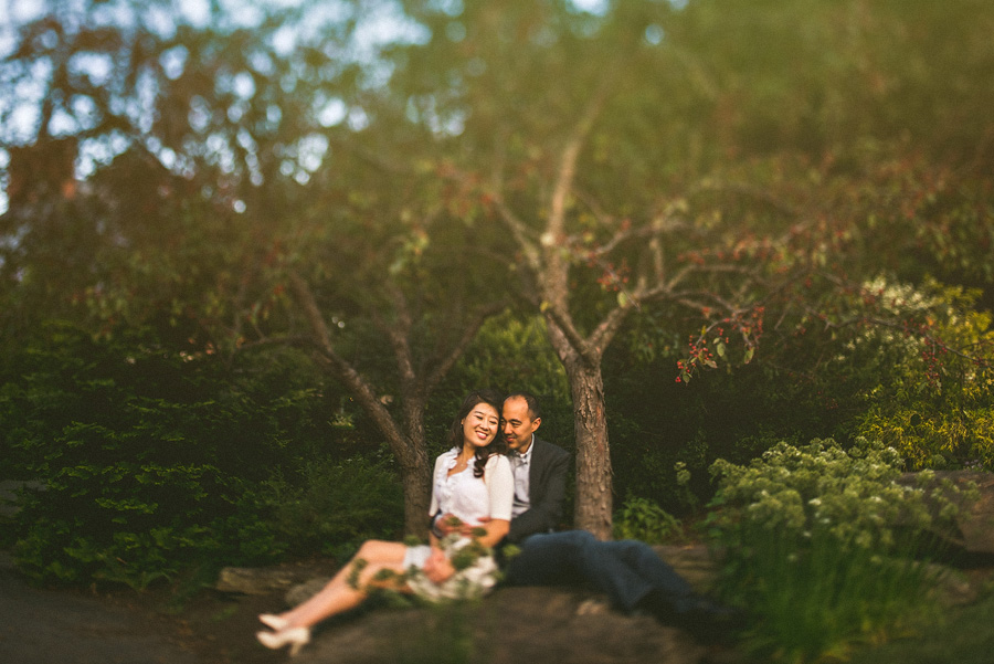couple sitting on a rock in the woods laughing with eachother