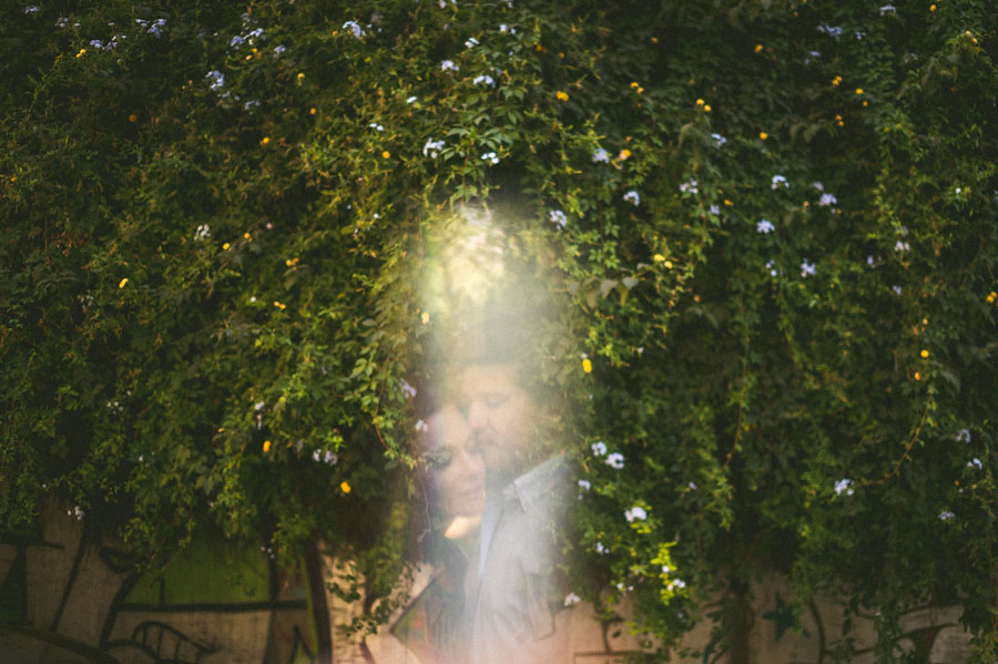 A soft-focus image of a person partially obscured by sunlit foliage with small white flowers, enhanced using advanced software for image processing.