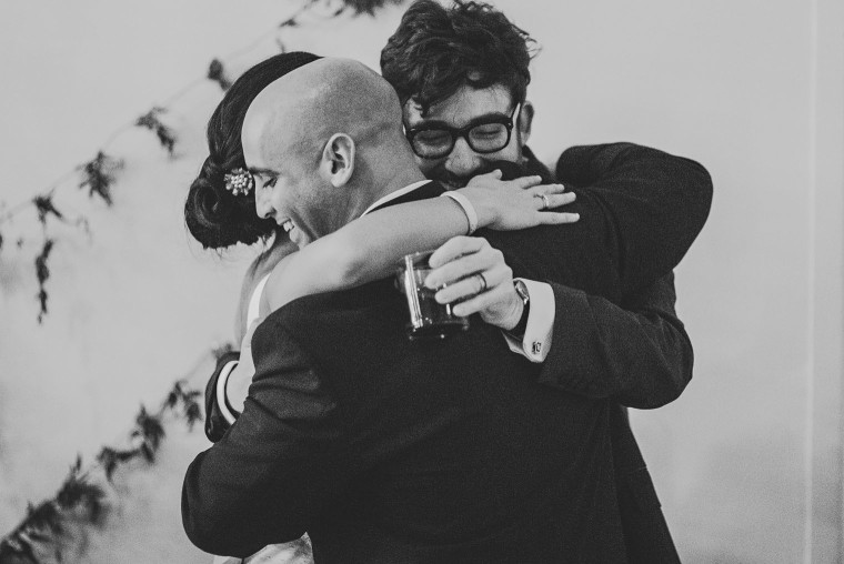 brid eand groom hugging best man