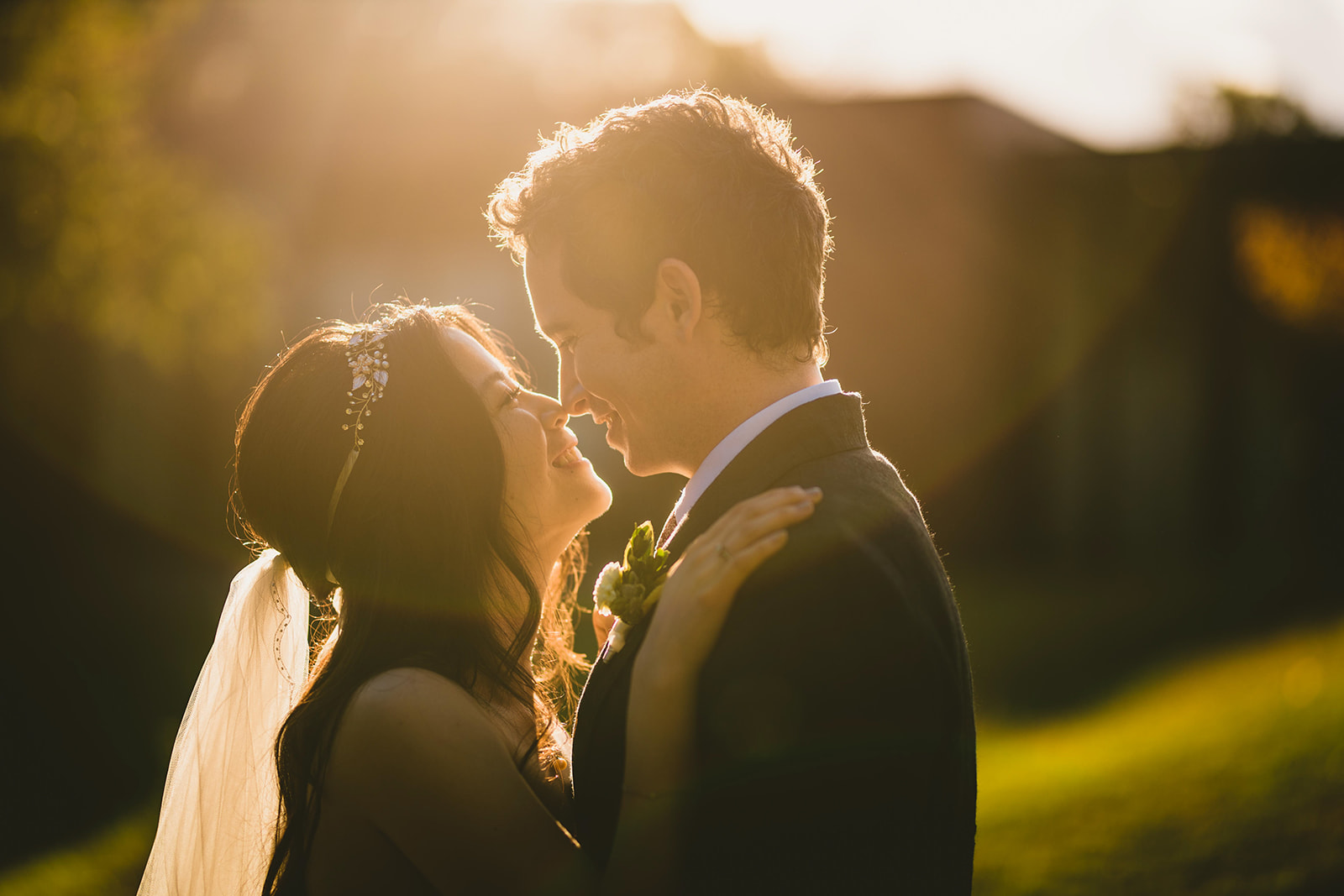 A couple in wedding attire smile and embrace each other in a sunlit outdoor setting, as if capturing a moment straight out of an elegant Auto Draft.