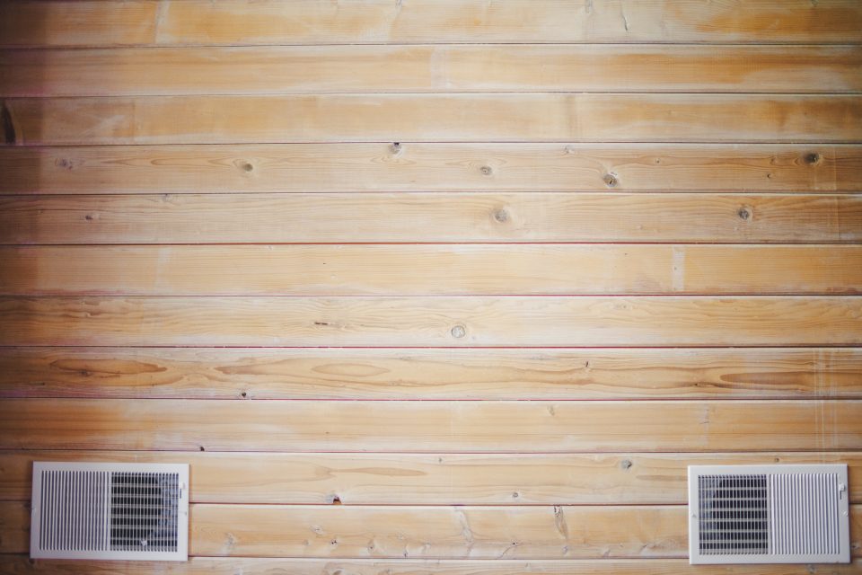 A wooden wall with horizontal plank design features two rectangular air vents near the bottom, reminiscent of the detailed craftsmanship discussed in a Canon 35 1.4 VCM lens review.