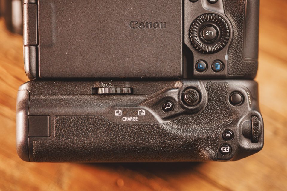 Close-up of a Canon DSLR camera featuring the back panel controls and a battery grip, placed on a wooden surface, demonstrating real-world use ideal for those inspired by our Canon R5 Mark ii Review.
