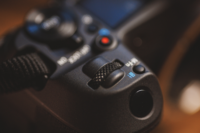 Close-up of a camera showing details of the shutter button, a control dial, and a strap, illustrating the Canon R5 Mark ii Review in real-world use.