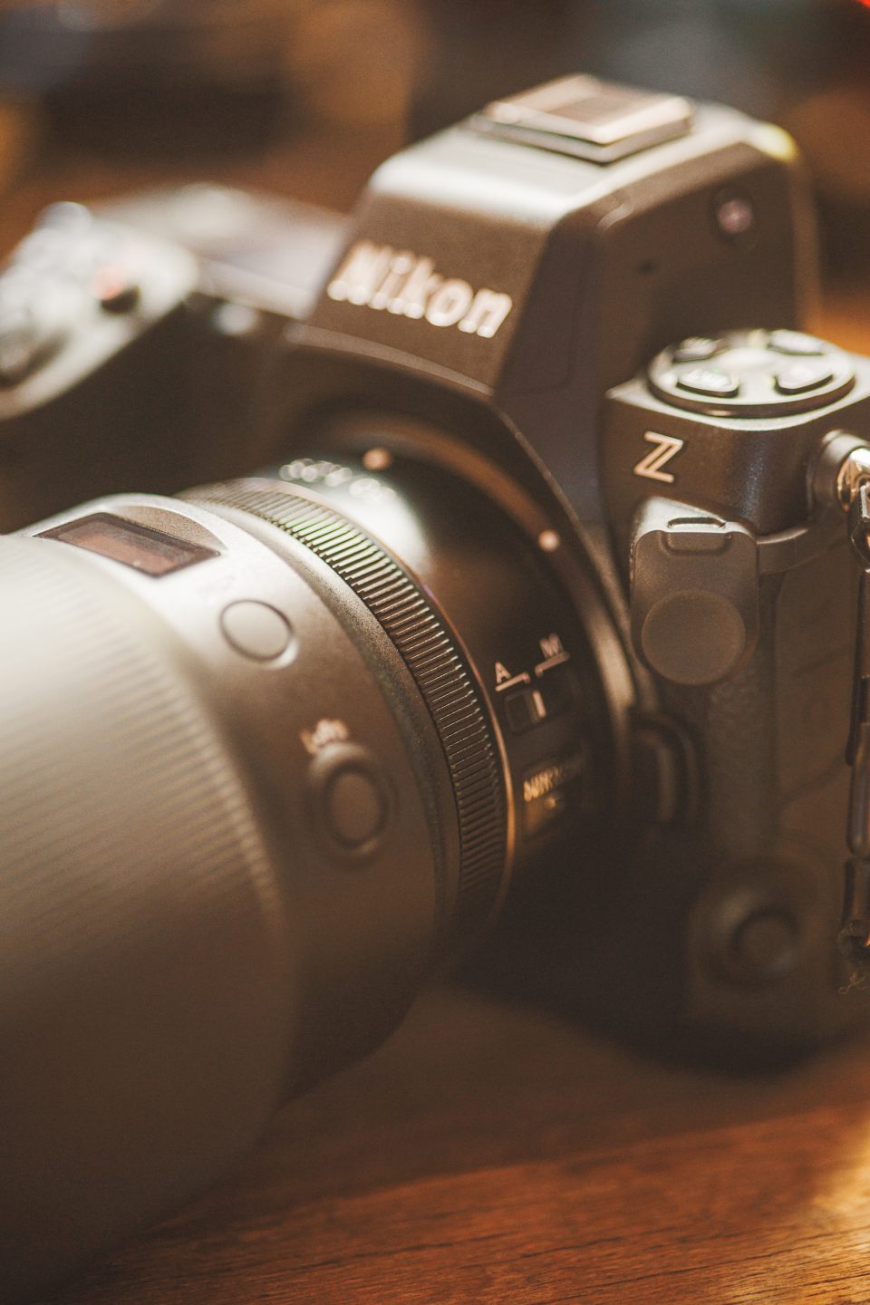 A close-up of a Nikon Z series camera with a large lens attached rests on a wooden surface, capturing the world in auto mode for perfect precision.