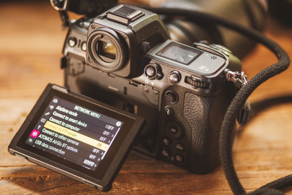 A digital camera with an open articulated screen showcasing its advanced network menu settings for seamless connectivity.
