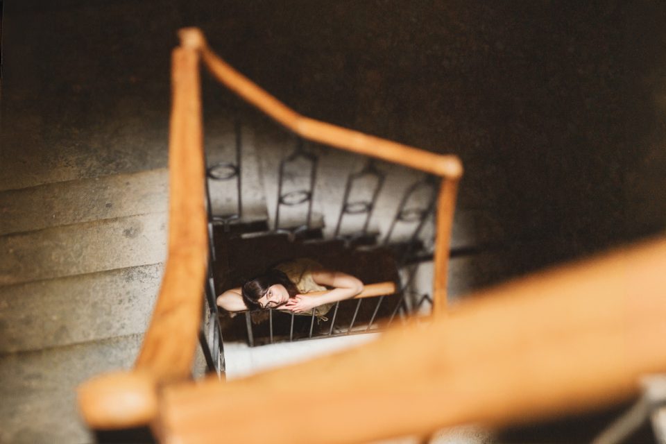 Person leaning on a stair railing, viewed from above in a spiral staircase.
