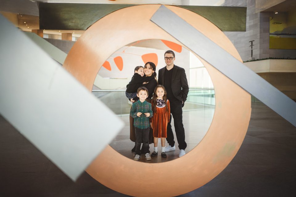 A group of people stand together, framed by a circular art piece with geometric shapes in a modern indoor setting.