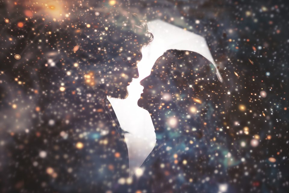 Silhouettes of a man and woman facing each other with a cosmic, starry background effect.