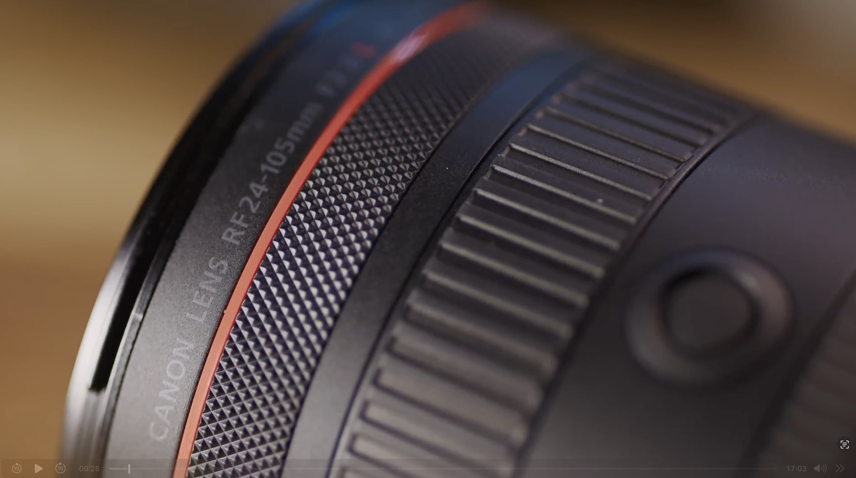 Close-up of a Canon RF 24-105mm camera lens showing textured focus and zoom rings, with lens specifications visible along the side.