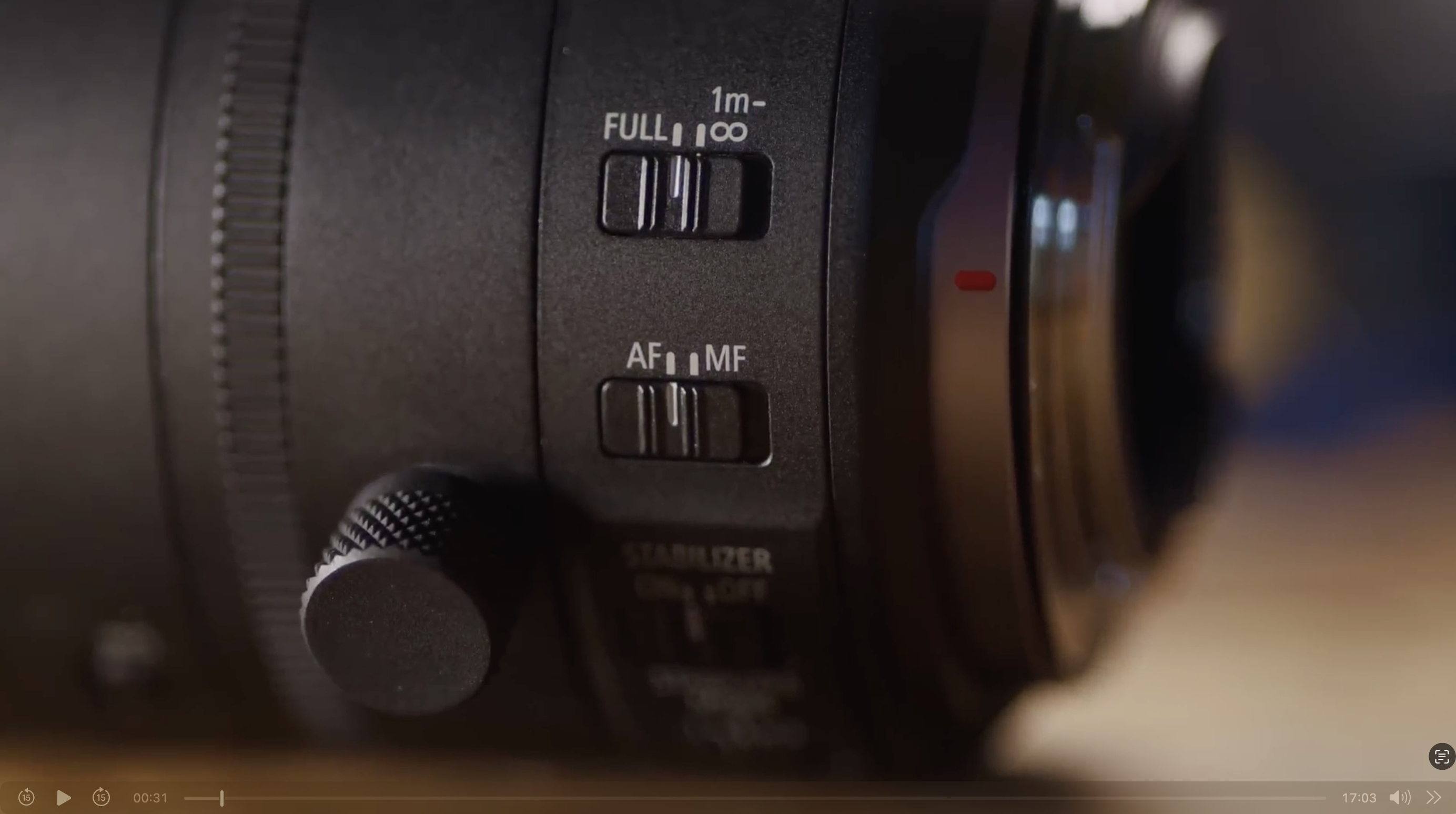 Close-up of a camera lens showing switches labeled FULL/1m-∞ and AF/MF, along with a focus ring and part of the lens barrel.