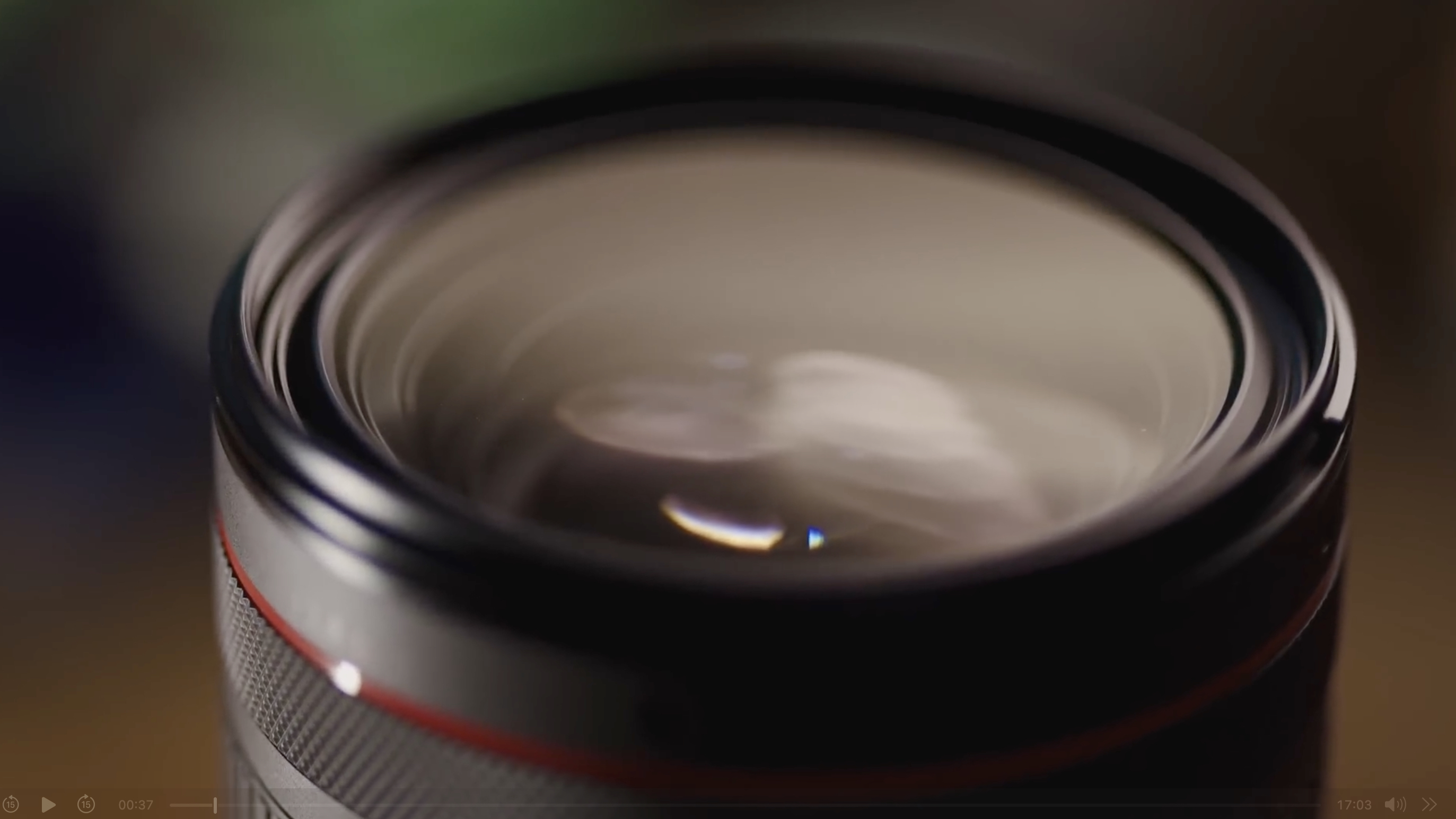 Close-up view of a camera lens with visible glass elements and a red ring near the edge of the barrel.