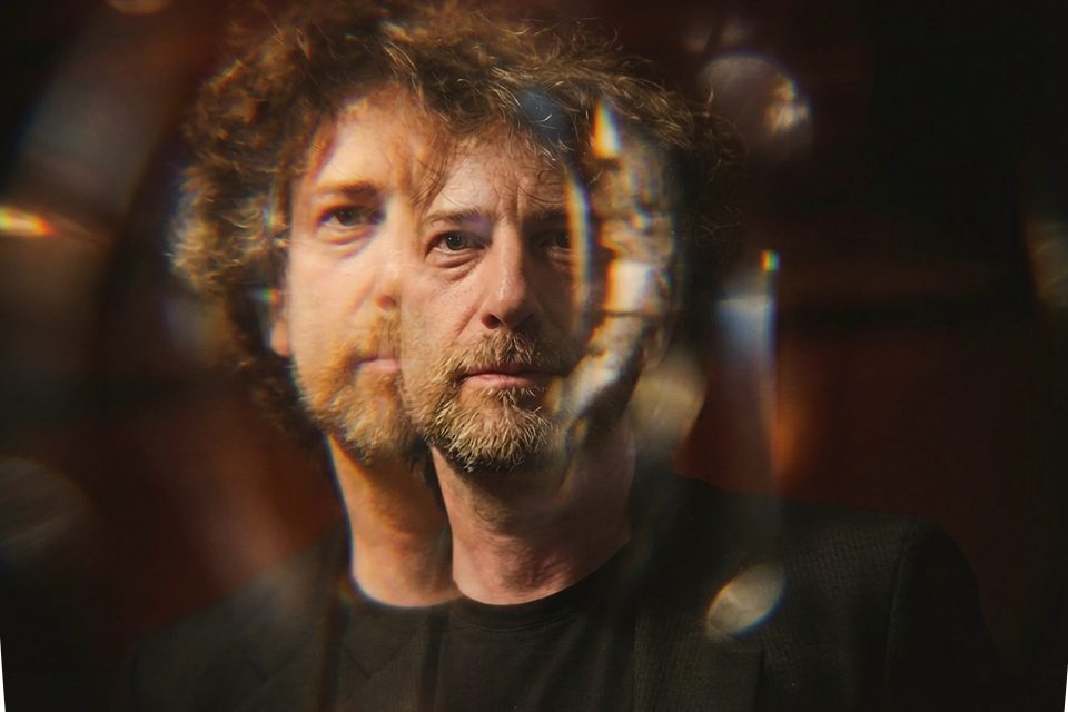 A man with curly hair and a beard is seen through a reflective, multi-layered surface, creating a double image effect with blurred and overlapping features, captured expertly by a dc portrait photographer. A man with curly hair and a beard is seen through a reflective, multi-layered surface, creating a double image effect with blurred and overlapping features, captured expertly by a dc portrait photographer.