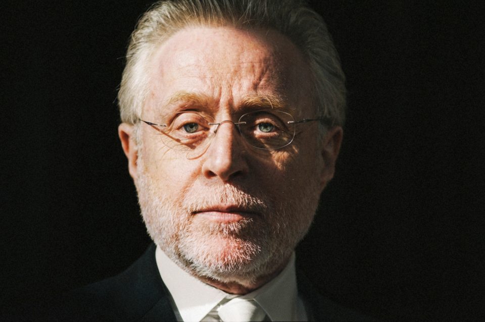 A man with gray hair, a beard, and glasses wearing a dark suit and white shirt faces the camera against a dark background in this striking shot by a DC portrait photographer. A man with gray hair, a beard, and glasses wearing a dark suit and white shirt faces the camera against a dark background in this striking shot by a DC portrait photographer.