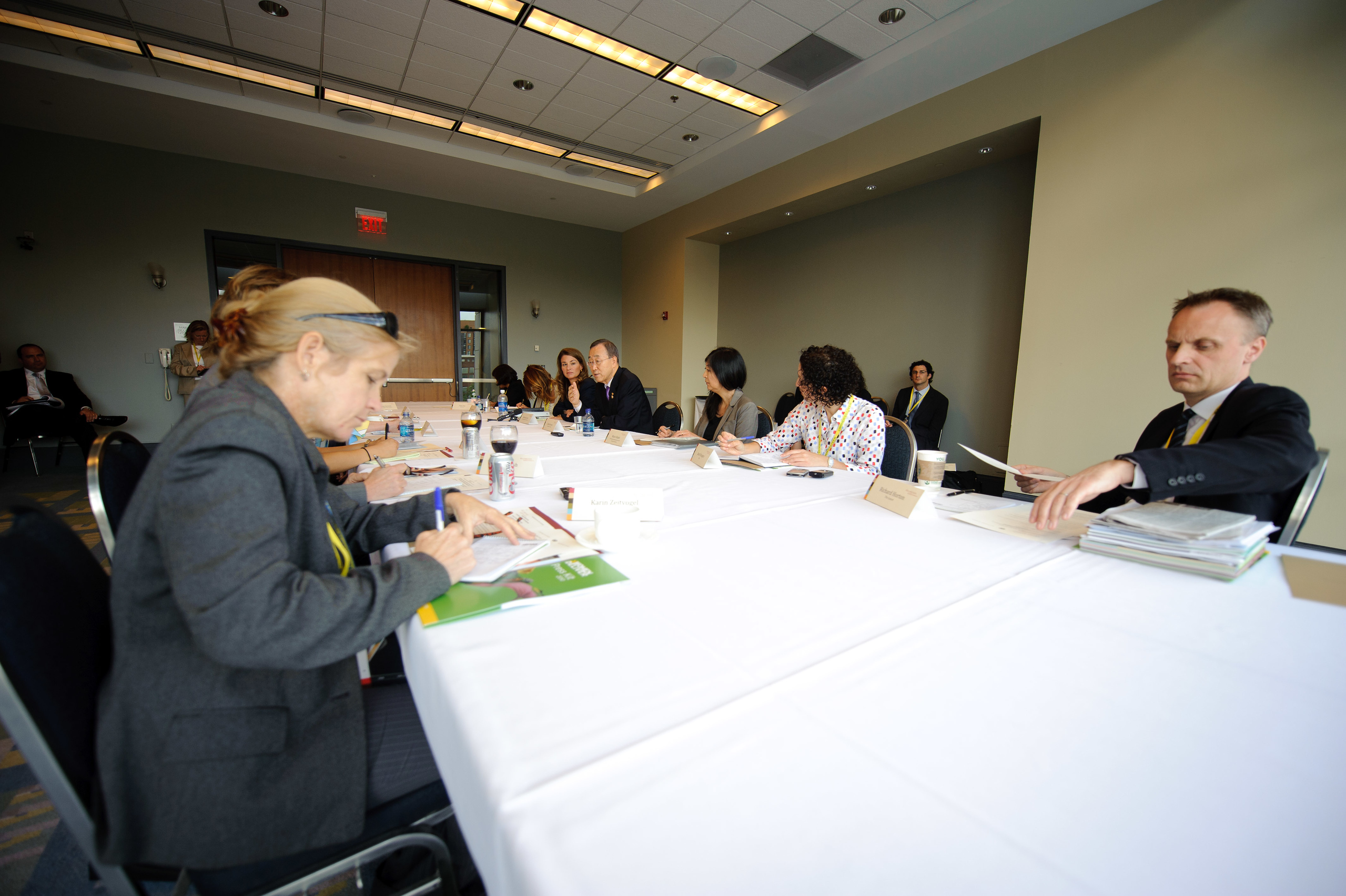 People seated around a conference table in a meeting room, engaged in discussion and paperwork.
