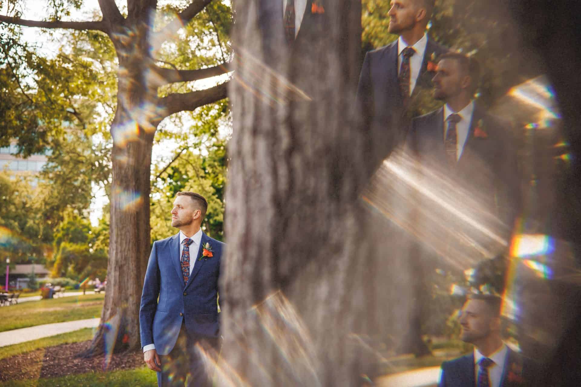 Groom in a blue suit walking through a city park during a Planet Word wedding, seen through a prism effect