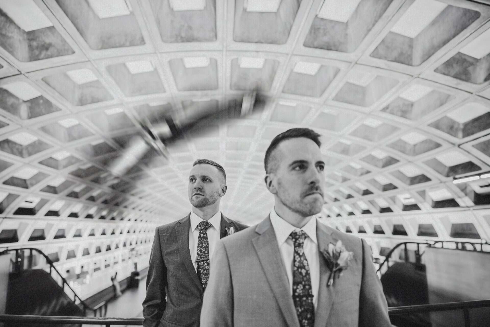 Black and white portrait of two grooms under the curved coffered ceiling of a Washington DC Metro station